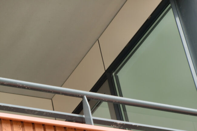 Zwevende luifel met ivoorkleurige UniKern® biobased compactplaten bij appartementen in Rotterdam