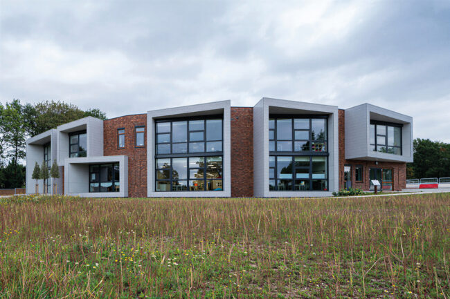 Gevelbekleding van UniKern® compactplaten bij IKC Dorpsschool Rozendaal rondom grote glaspuien in RAL 7035.
