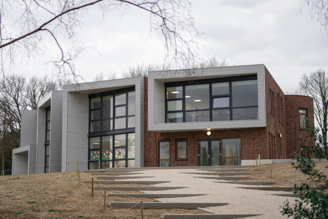 Gevelbekleding van UniKern® compactplaten bij IKC Dorpsschool Rozendaal rondom grote glaspuien in RAL 7035.