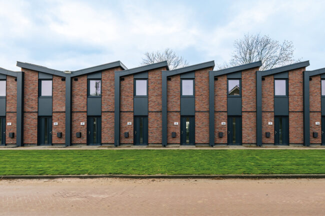Nieuwbouw Heerewaarden met opvallende zaagtanddaken, antraciete UniKern® geveldetails en rode gevelstenen.