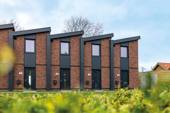 Nieuwbouw Heerewaarden met opvallende zaagtanddaken, antraciete UniKern® geveldetails en rode gevelstenen.
