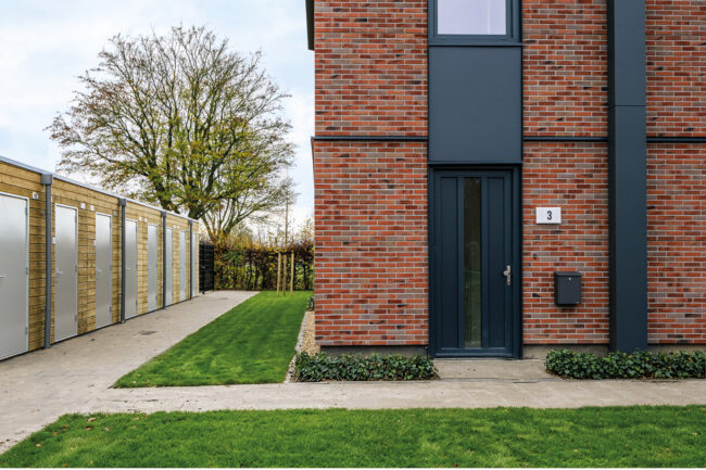 Nieuwbouw Heerewaarden met opvallende zaagtanddaken, antraciete UniKern® geveldetails en rode gevelstenen.